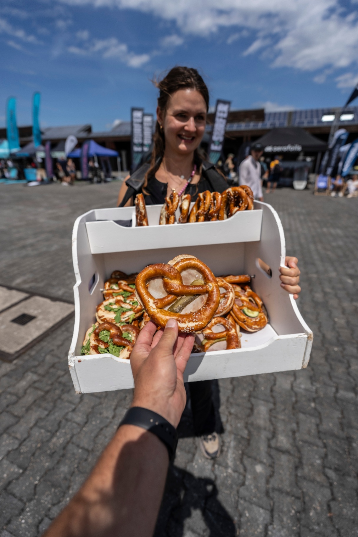Frau mit Brezn-Bauchladen auf dem Eventgelände — Community-Moment