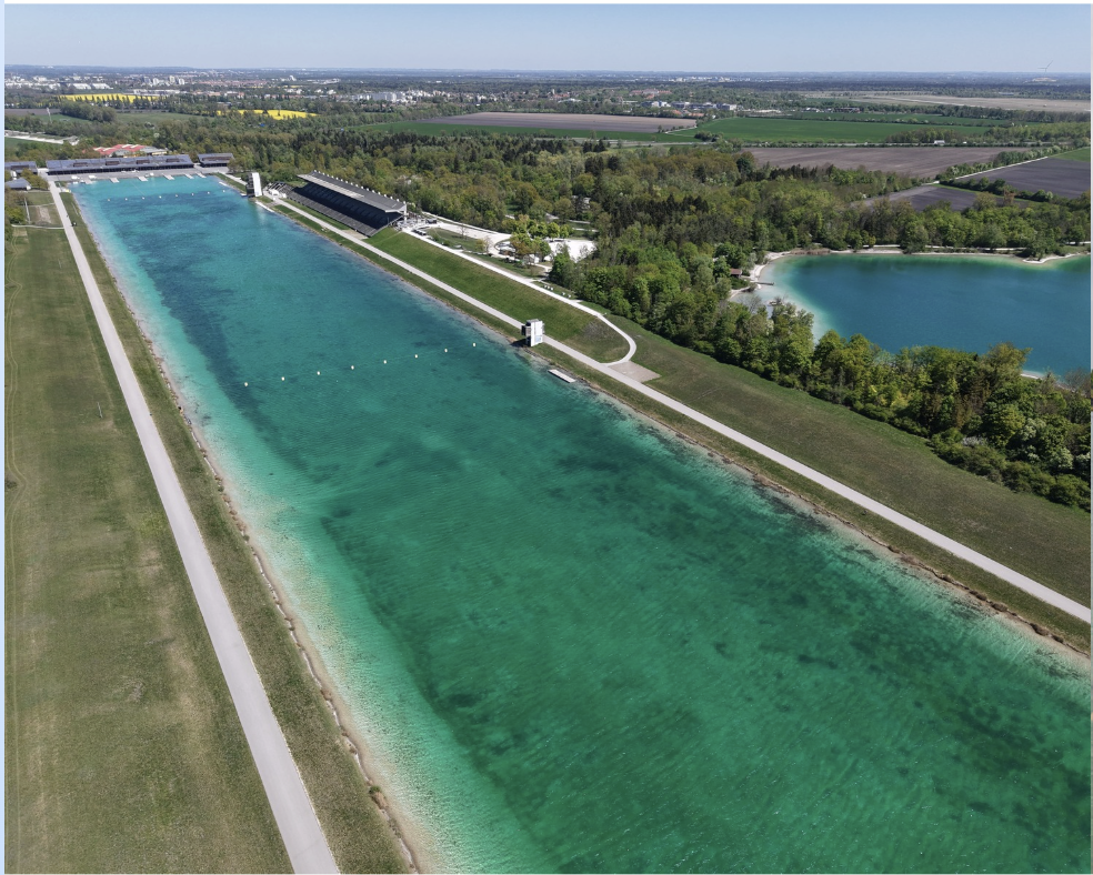 Luftaufnahme der Regattaanlage mit historischer Tribüne und türkisem Wasser