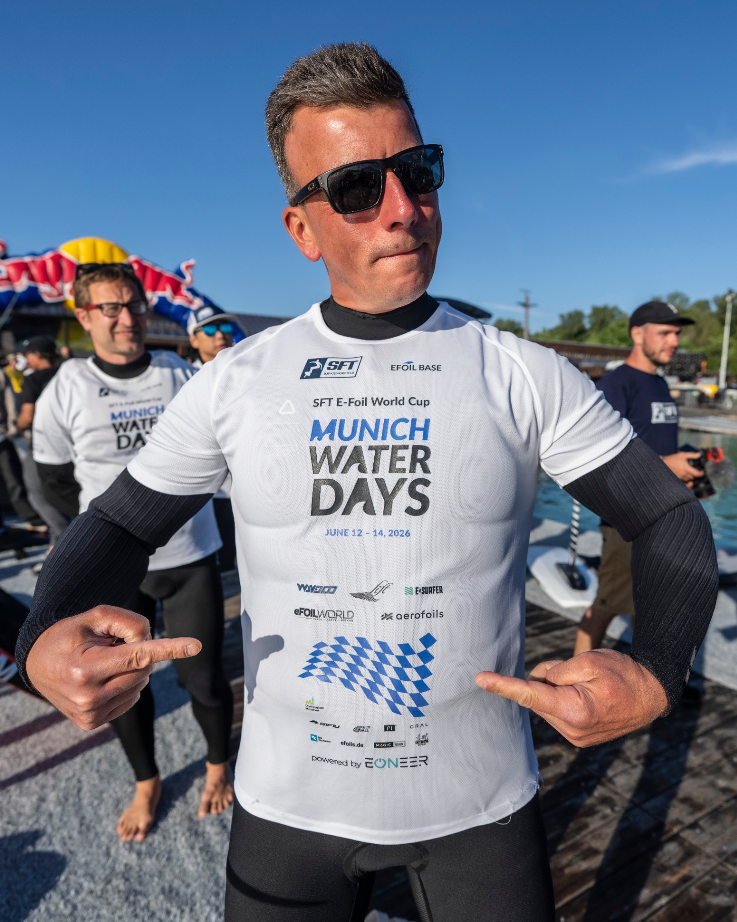 Athlet zeigt auf sein Munich-Water-Days-Trikot mit den Partner-Logos