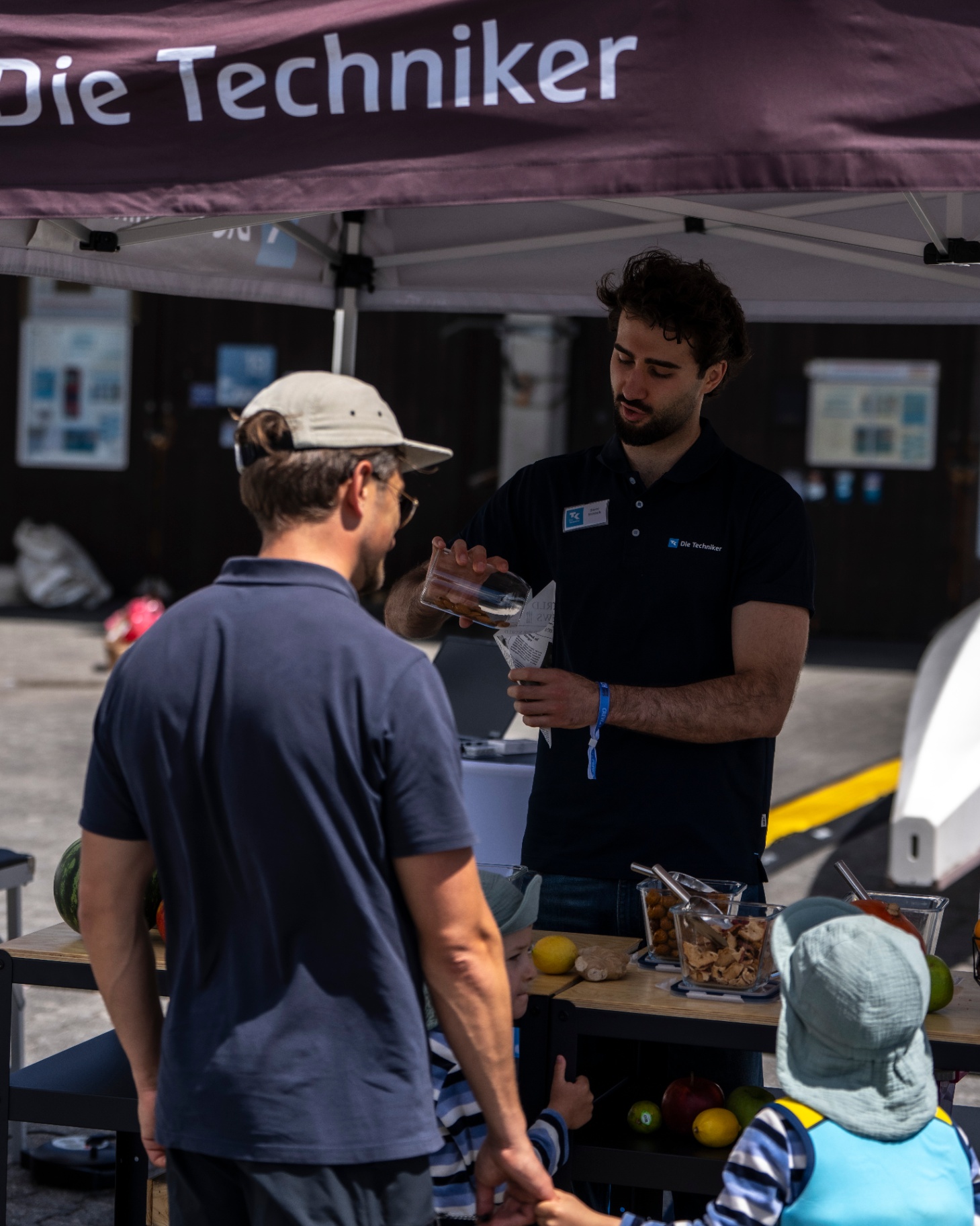 Familie im Gespräch am Stand von Die Techniker — Community-Atmosphäre