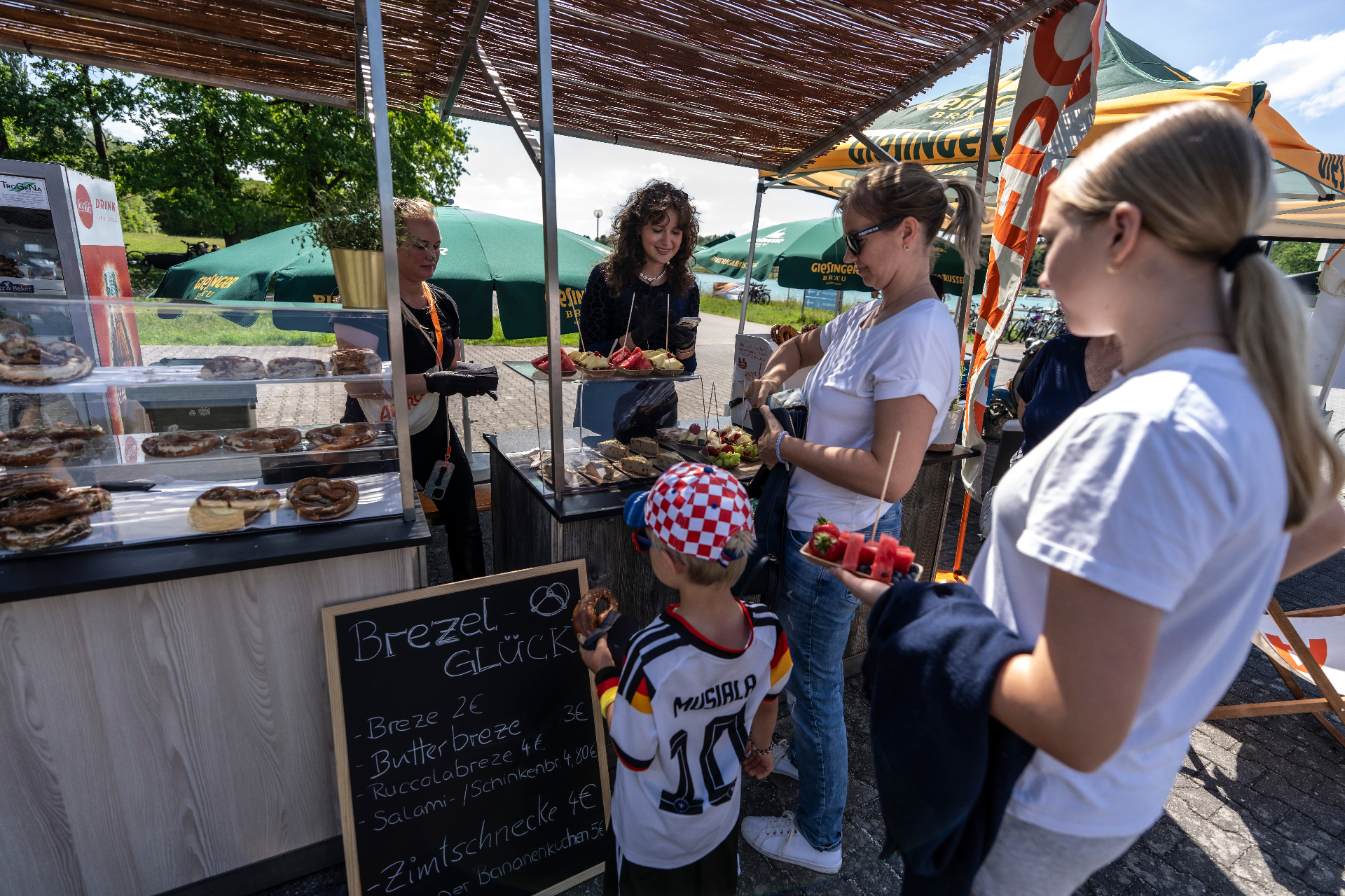 Familien holen sich Brezen, Snacks und Obst am Food-Stand