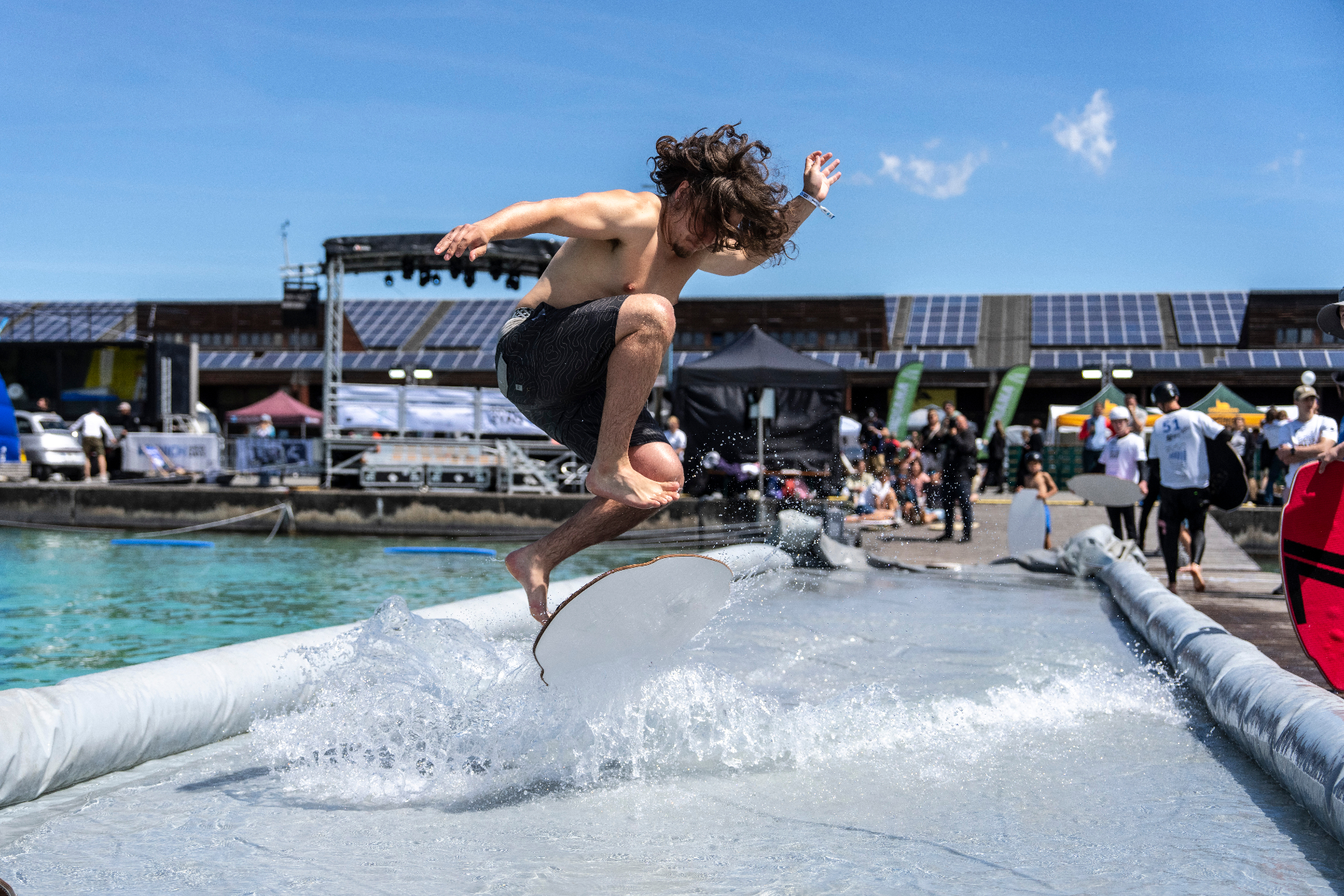 Rider gleitet über den Skimpool bei den Munich Water Days, Bühne und Zuschauer im Hintergrund