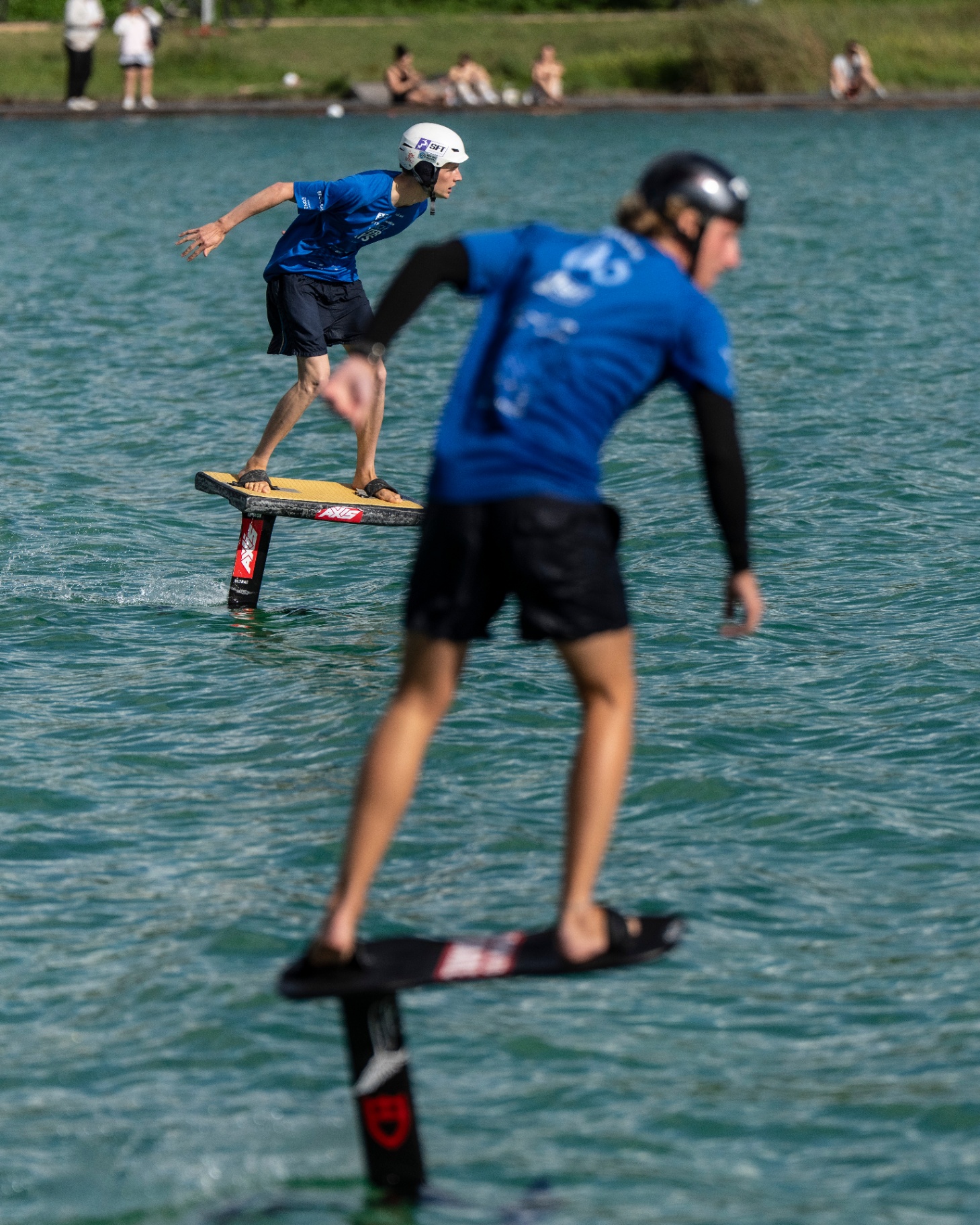 Zwei Pumpfoil-Rider gleiten hintereinander über das Wasser der Regattastrecke