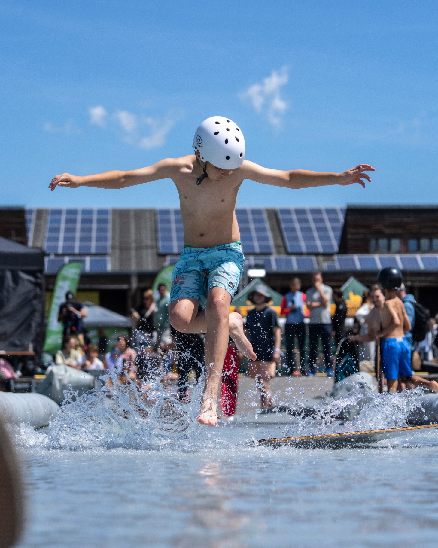 Junger Rider mit weißem Helm springt lachend durch den Splash